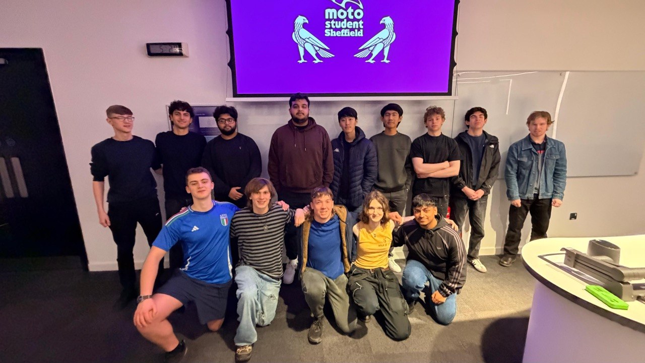 The MotoStudent Sheffield team assembled in a lecture theatre, with the team logo projected behind them.